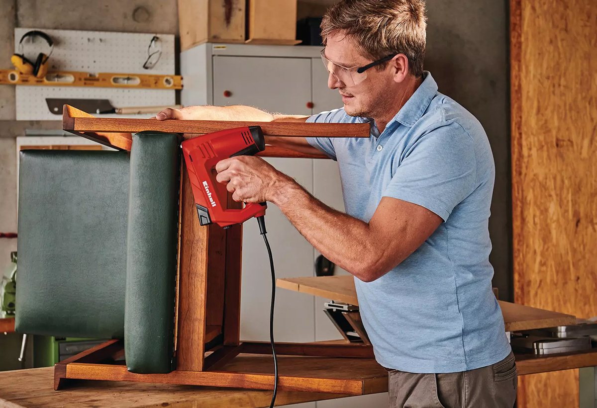 Απεικονίζεται ένας άνδρας να χρησιμοποιεί το καρφωτικό στο πόδι μιας καρέκλας.